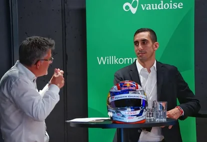 S&eacute;bastien Buemi in conversation beside his race helmet at a Vaudoise event