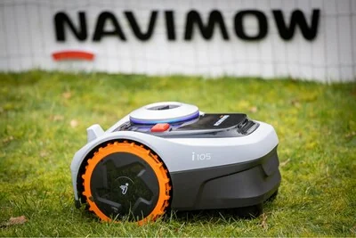 Segway Navimow robotic mower on grass in front of a Navimow banner